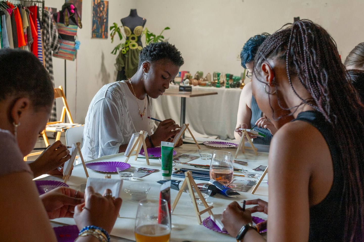 Groupe diversifié de personnes peignant des toiles à une table d'atelier d'art.