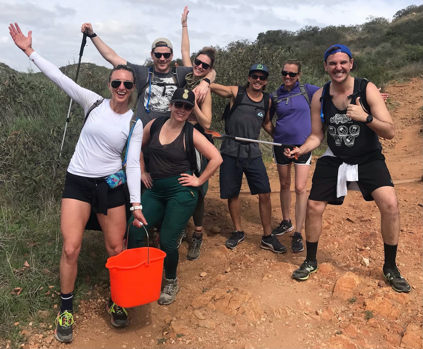 Des randonneurs souriants sur un sentier lors d'un événement de nettoyage en plein air.